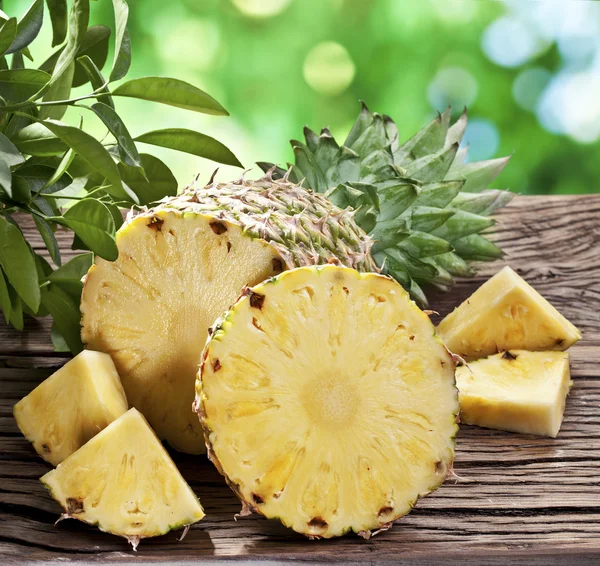 Pineapple with slices on a wooden table. — Stock Photo, Image