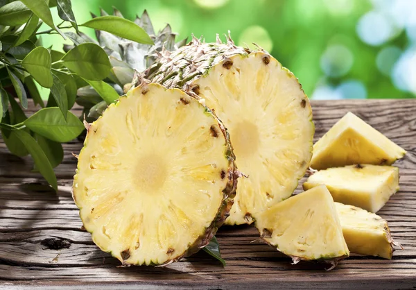 Piña con rodajas en una mesa de madera . — Foto de Stock