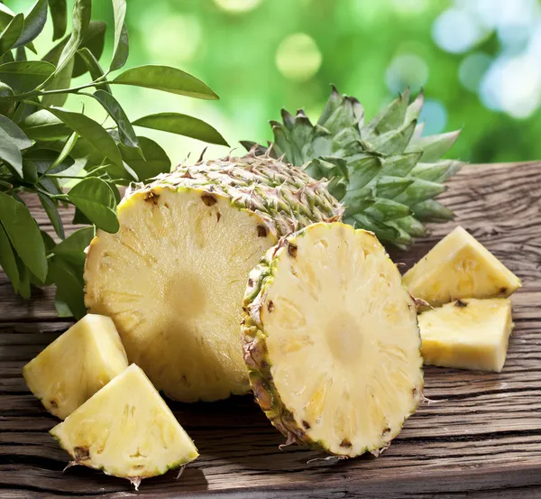 Pineapple with slices on a wooden table. — Stock Photo, Image