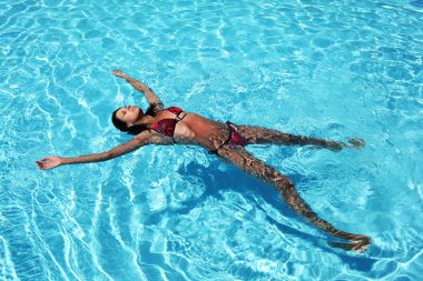 Havuzda dinlenen genç kadın.