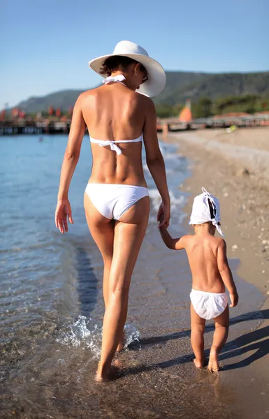 Mor och dotter promenader längs stranden. — Stockfoto