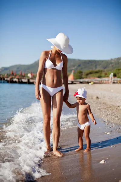 Mutter und Tochter gehen am Strand entlang. — Stockfoto