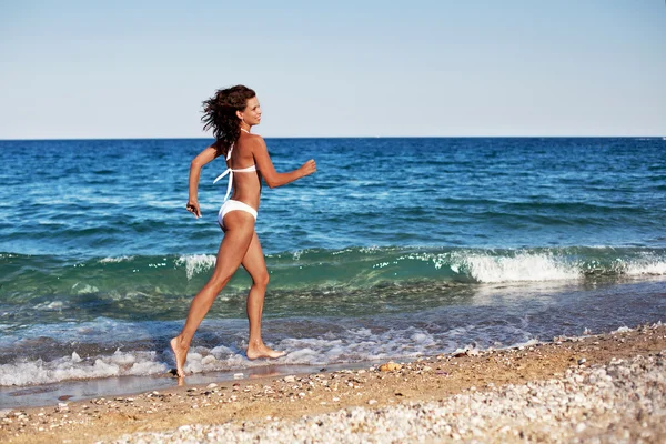 Молода жінка біжить уздовж пляжу . — стокове фото
