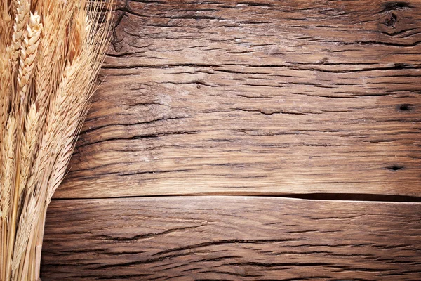 Orejas de trigo sobre una vieja mesa de madera . — Foto de Stock