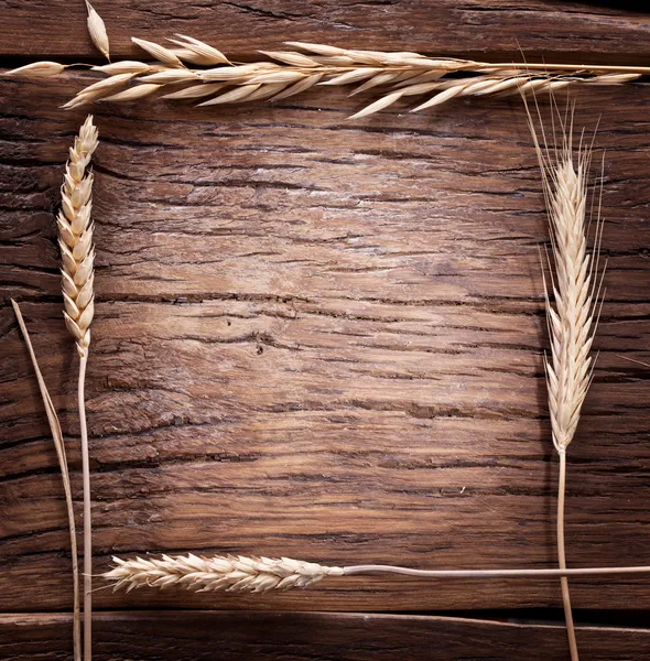 Ears of wheat made as frame on old wooden table. — Stock Photo, Image