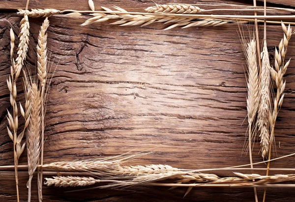 Уши из пшеницы, сделанные как рама на старом деревянном столе . — стоковое фото