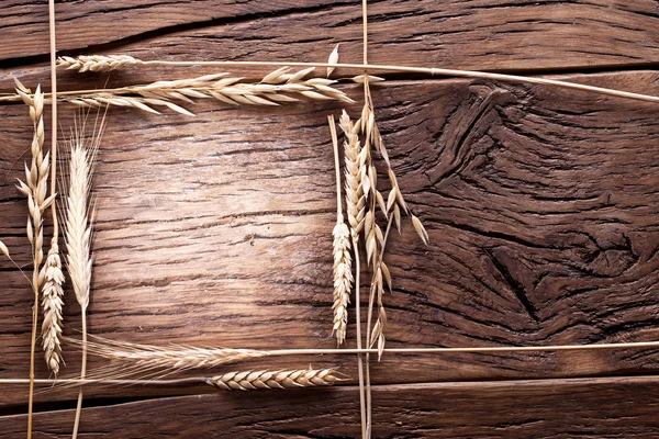 Orelhas de trigo na velha mesa de madeira . — Fotografia de Stock