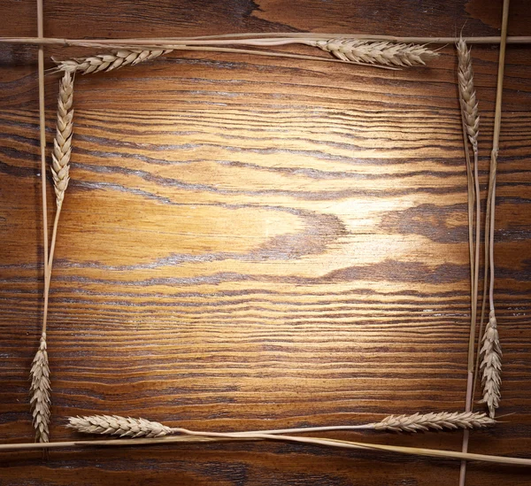 Eski ahşap masa üzerinde çerçeve olarak yapılan buğday kulaklar. — Stok fotoğraf