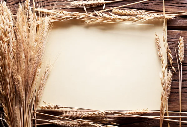 Ears of wheat in the form frame on old wooden table. — Stock Photo, Image