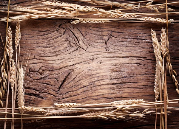 Eski ahşap masa üzerinde form çerçevesinde buğday kulaklar. — Stok fotoğraf