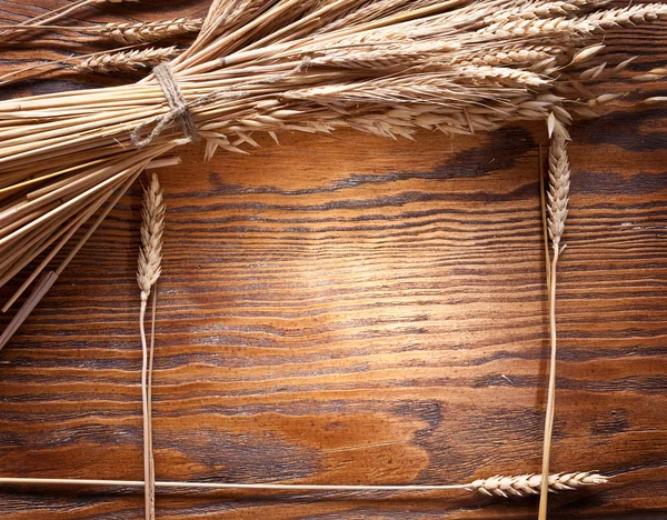 Oren van tarwe op oude houten tafel. — Stockfoto