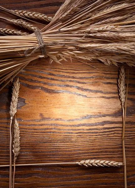 Oren van tarwe op oude houten tafel. — Stockfoto