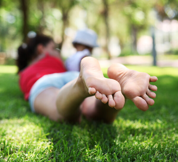 Young woman lies on green grass in the park.