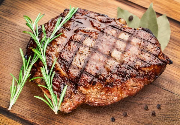 Hovězí steak na dřevěný stůl. — Stock fotografie