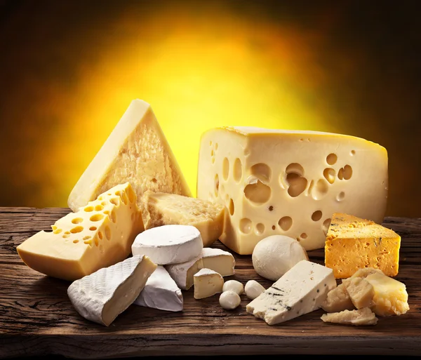 Diferentes tipos de queso sobre una vieja mesa de madera . — Foto de Stock