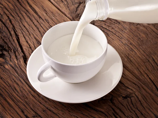Şişe beyaz fincan dökülen süt. — Stok fotoğraf