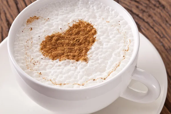 Xícara de cappuccino com canela moída na forma de coração . — Fotografia de Stock