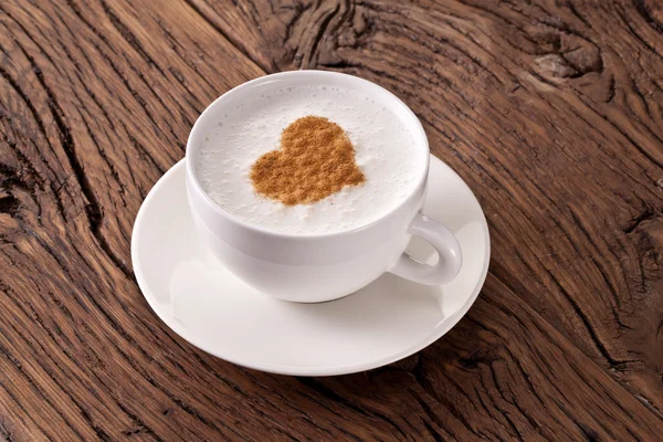 Xícara de cappuccino com canela moída na forma de coração . — Fotografia de Stock