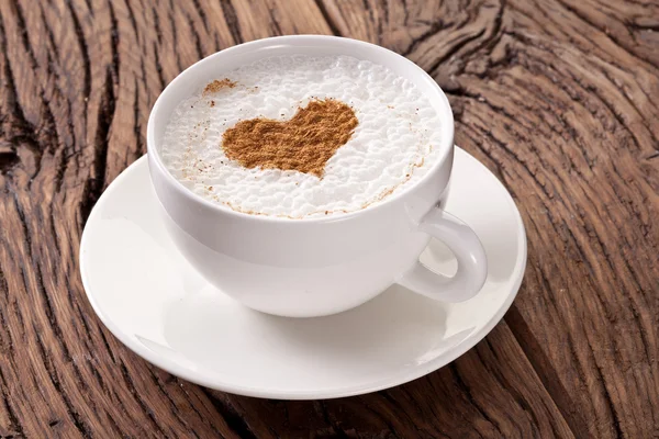 Xícara de cappuccino com canela moída na forma de coração . — Fotografia de Stock