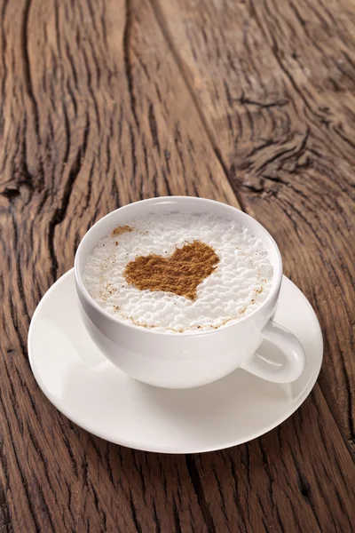 Tasse Cappuccino mit gemahlenem Zimt in Herzform. — Stockfoto