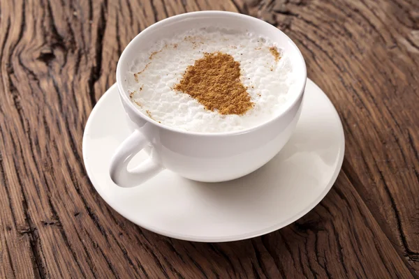 Tasse Cappuccino mit gemahlenem Zimt in Herzform. — Stockfoto