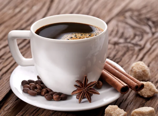 Tasse Kaffee mit Kaffeebohnen und Gewürzen daneben. — Stockfoto