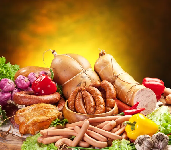 Still-life with sausage products, vegetables and herbs. Royalty Free Stock Photos