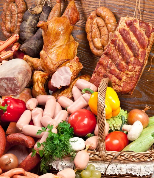 Variety of sausage products and basket with vegetables. Stock Picture