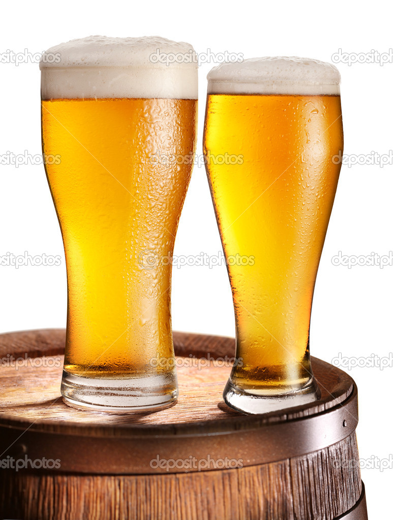 Two glasses of beer over woden barrel.
