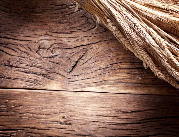 Orelhas de trigo na velha mesa de madeira . — Fotografia de Stock