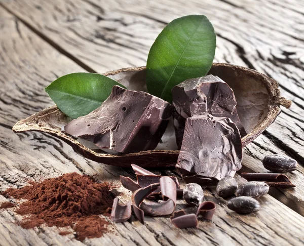 Chocolate and cocoa bean over wooden table. — Stock Photo, Image