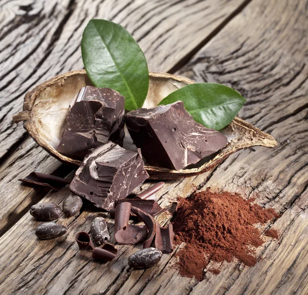 Chocolate and cocoa bean over wooden table. — Stock Photo, Image