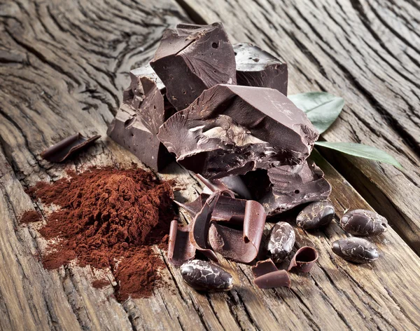 Chocolate and cocoa bean over wooden table. — Stock Photo, Image