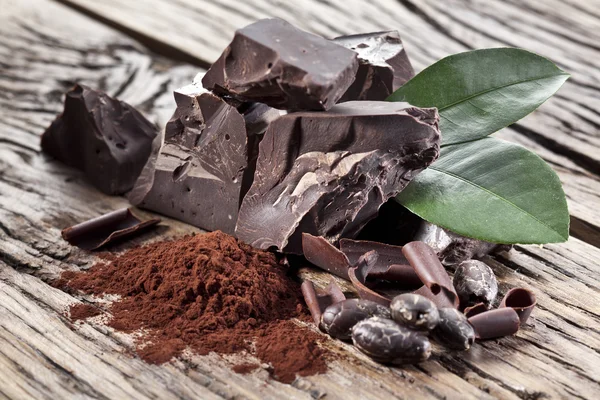 Chocolate and cocoa bean over wooden table. — Stock Photo, Image