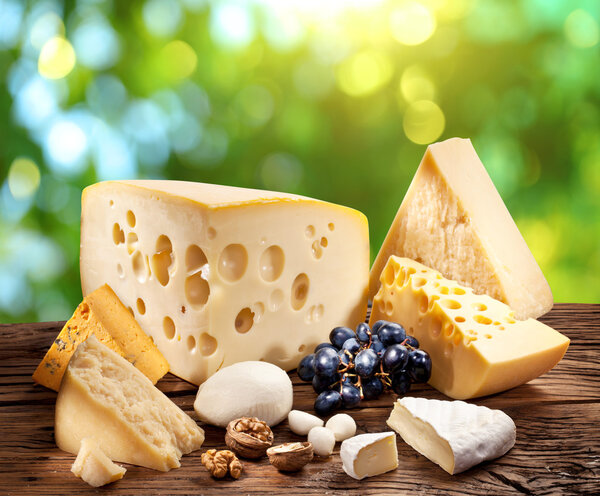 Different types of cheese over old wooden table.