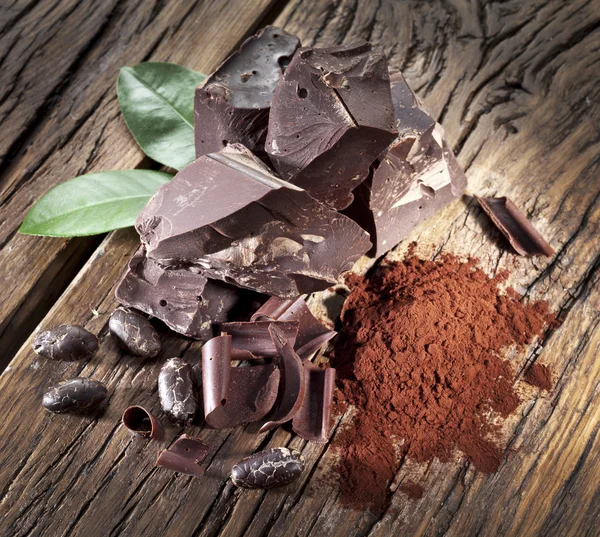 Chocolate and cocoa bean over wooden table. — Stock Photo, Image