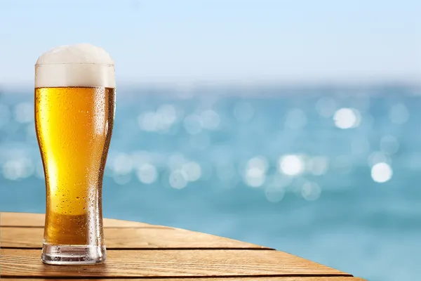 Beer glass on a blurred background of the sea. Stock Picture
