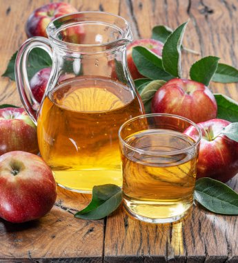 Koyu eski ahşap masada taze elma suyu ve organik elmalar..