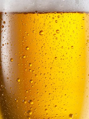 Soğutulmuş bir bardak bira. Bira bardağının soğuk yüzeyine küçük su damlaları düşer..