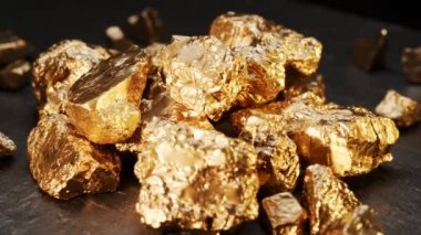 Siyah arka planda bir grup altın külçesinin etrafında dön. Büyük ve küçük altın taşlar, makro fotoğrafçılık..