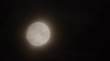 Tamamlanmamış Ay, gece gökyüzünde küçük bulutlar eşliğinde hareket eder..