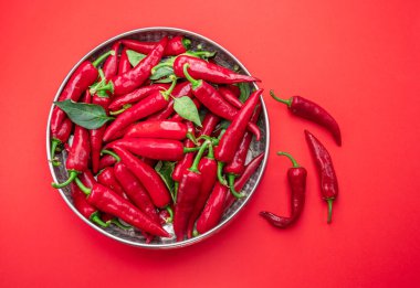 Kırmızı arka planda izole edilmiş metal tabakta taze kırmızı biber. Üst görünüm.