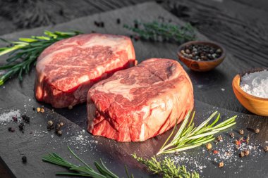 Gri tahtada tuzlu ve otlu çiğ pirzola bifteği. Üst görünüm.