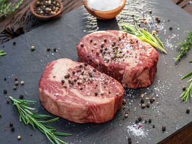 Gri tahtada tuzlu ve otlu çiğ pirzola bifteği. Üst görünüm.