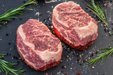 Gri tahtada tuzlu ve otlu çiğ pirzola bifteği. Üst görünüm.
