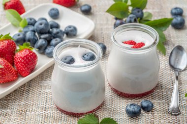 Sade yoğurt ve masada böğürtlen bulunan iki cam kap. Hafif yaz havası.