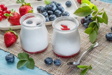 Sade yoğurt ve masada böğürtlen bulunan iki cam kap. Hafif yaz havası.
