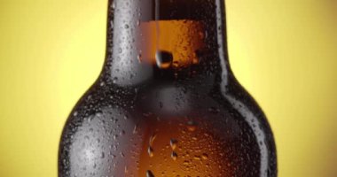 Bira yavaşça sisli bira şişesine damlıyor, kamerayı takip ederek. Sarı arkaplan.