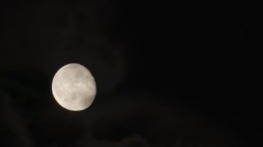 Tamamlanmamış Ay, gece gökyüzünde küçük bulutlar eşliğinde hareket eder..