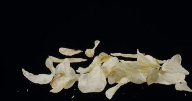 Doğal patates cipsi siyah arka planda yükselip alçalır. Yavaş Hareket 300 fps Blackmagic Ursa Pro G2.